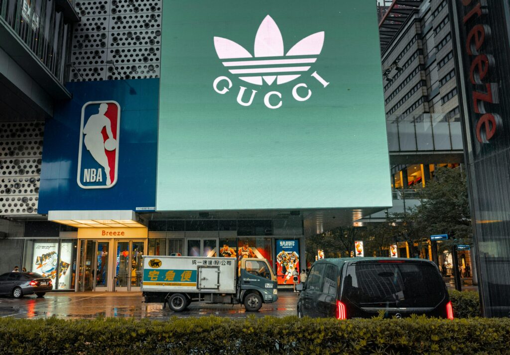 City street scene with Gucci billboard and NBA logo under rainy skies.